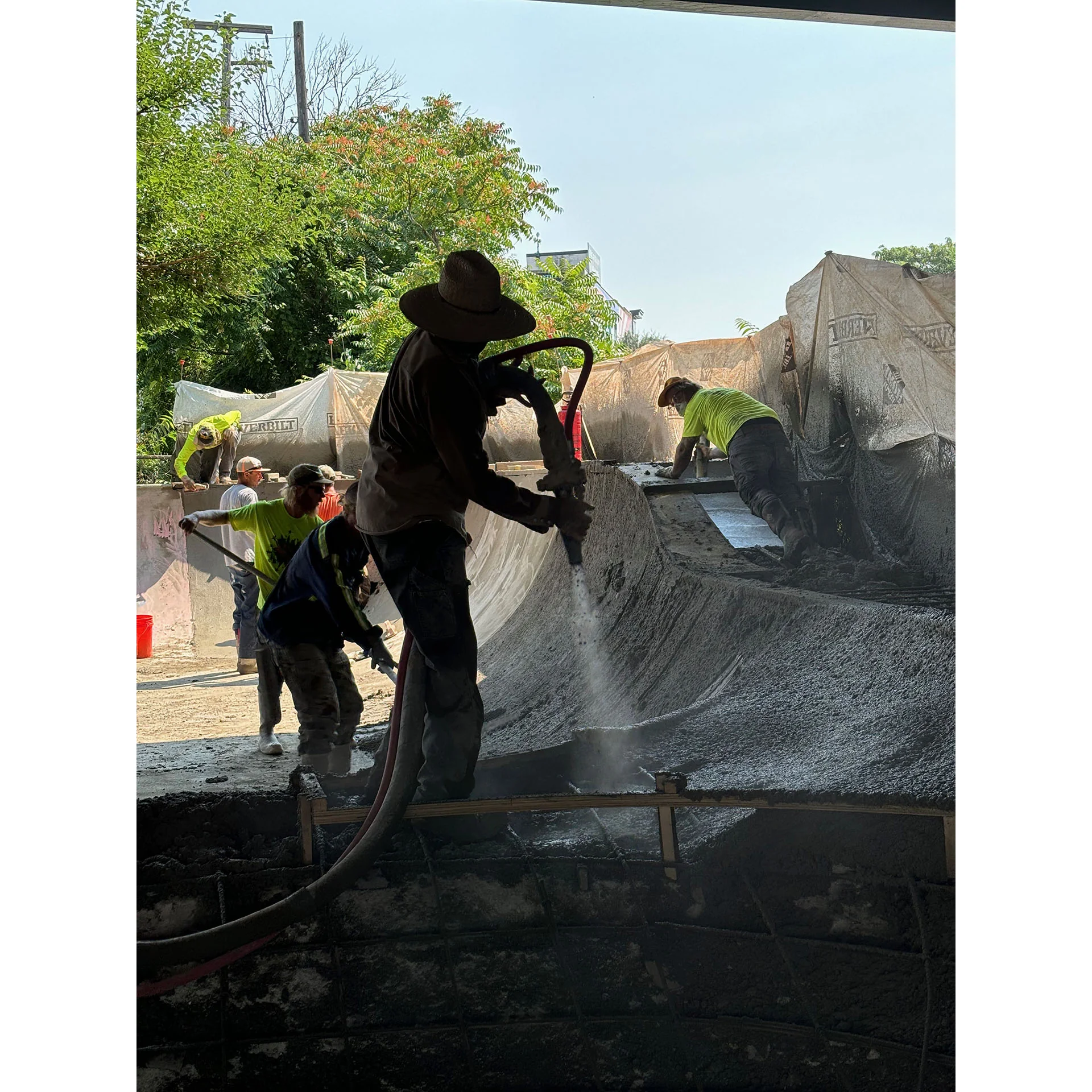 A photo of Scott Hughes shooting concrete from his pump hose into a framed skateboarding obstacle.